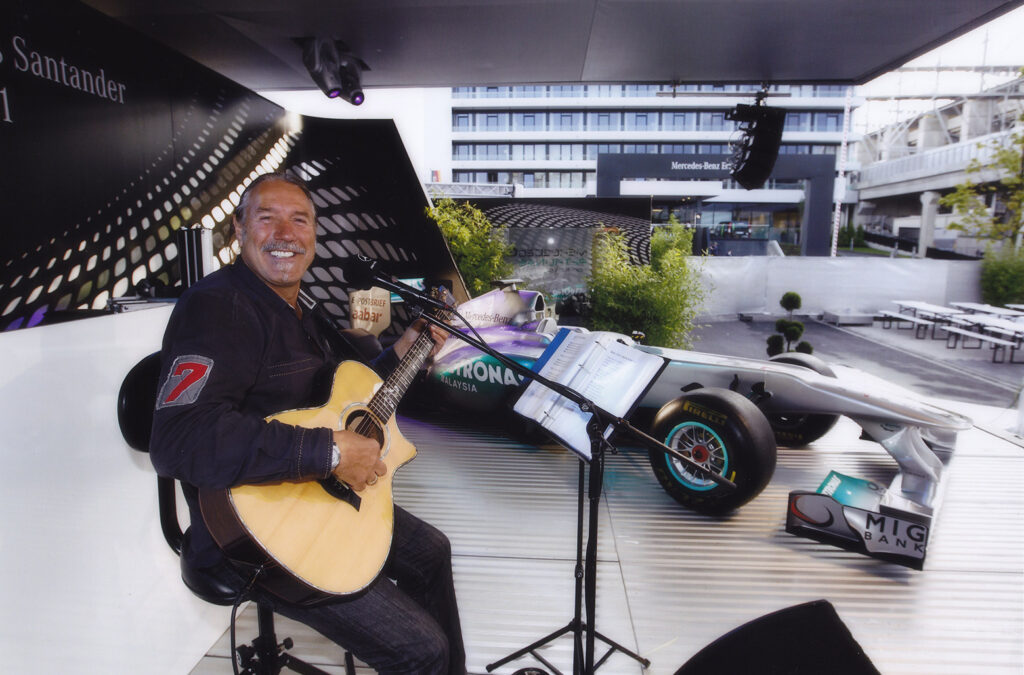 Uci Rausch begleitet eine Motorsportveranstaltung mit Livemusik vor einem Formel-1-Rennwagen
